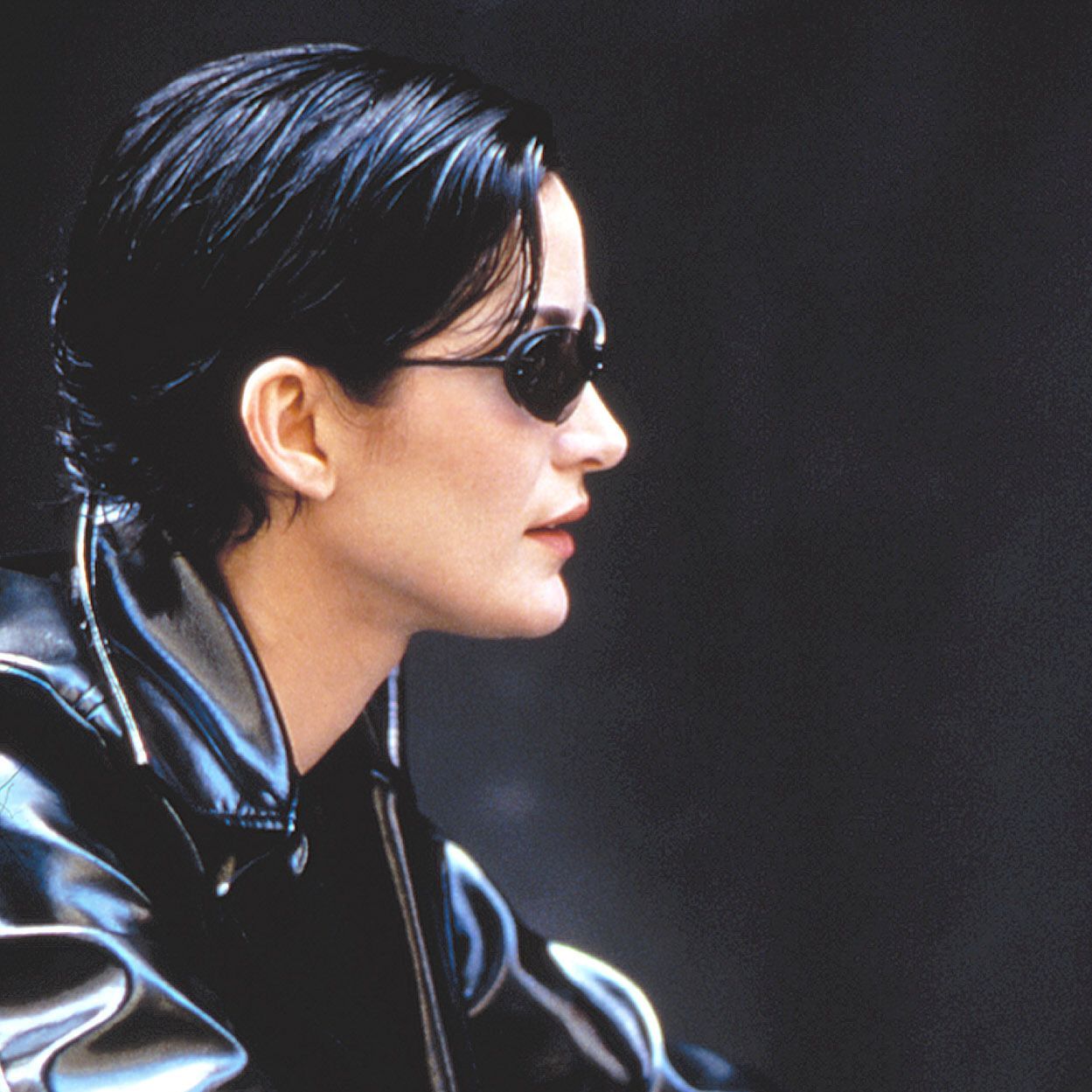 Carrie-Anne Moss jako Trinity s úzkými tmavými slunečními brýlemi ve filmu Matrix (1999)